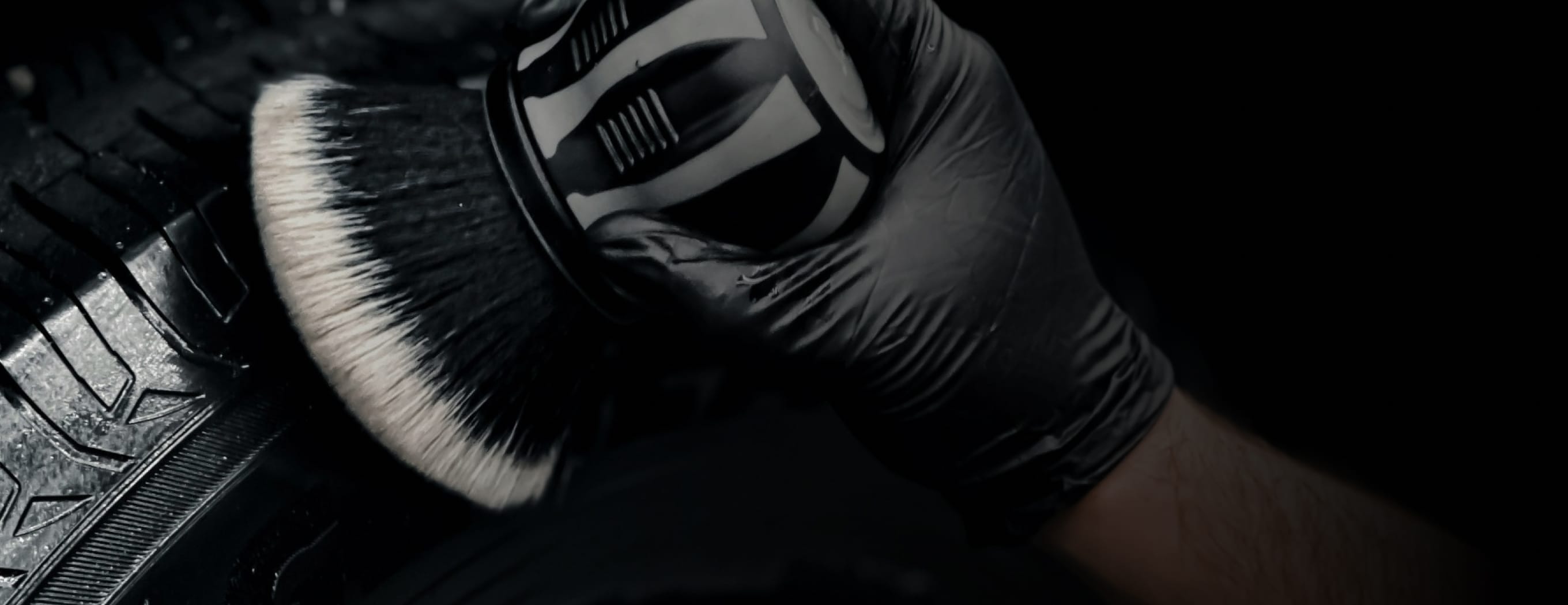 gloved hands brushing and waxing tire